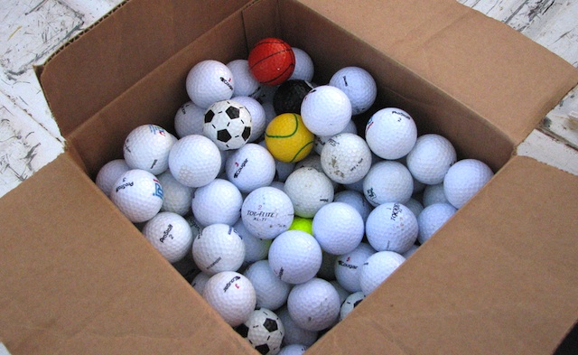 Box of golf balls, mostly white ones