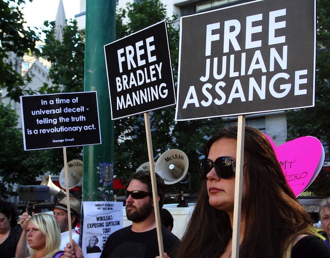 Protesters hold up "free Julian Assange" posters