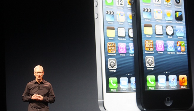 Apple CEO Tim Cook, with two giant iPhone 5 images behind him