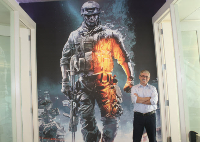 Frank Gibeau standing in front of promotional art for Battlefield.