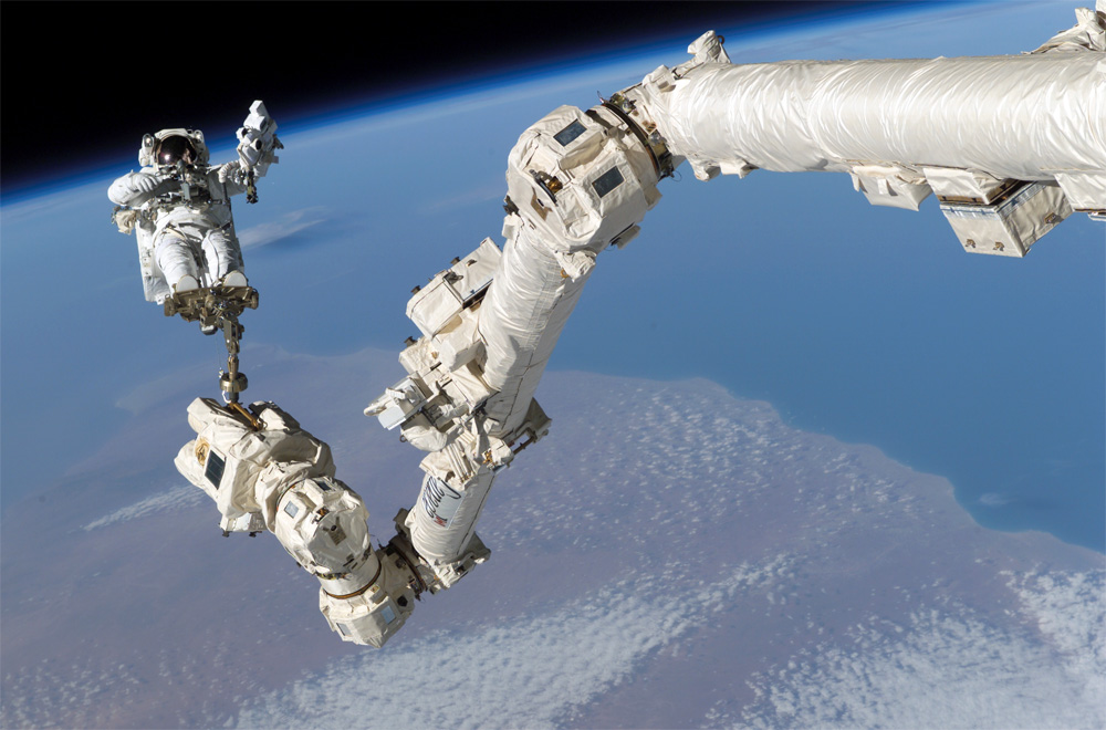 Astronaut Stephen K. Robinson anchored to the end of Canadarm2