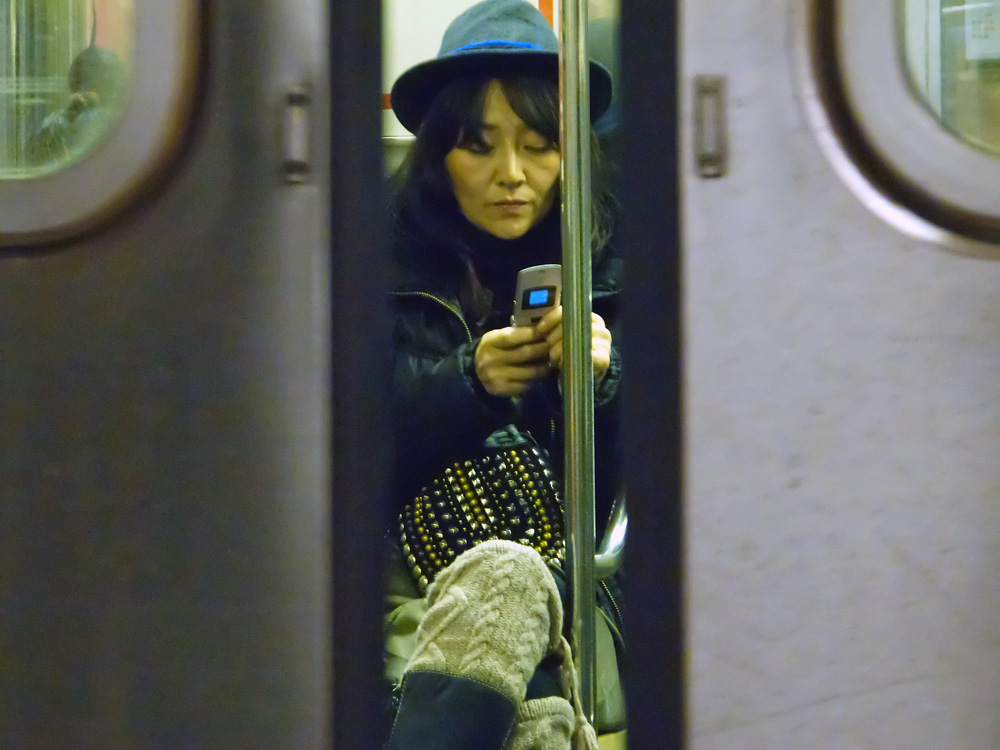 A woman uses her cell phone on a New York City subway train.