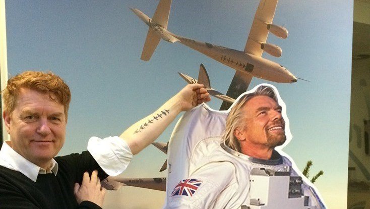 Would-be Virgin Galactic passenger Gisli Gislason shows off his 'DNA of Flight' tattoo in a photograph with a cut-out of Virgin's Richard Branson and SpaceShipTwo