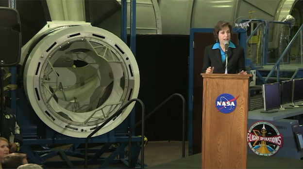 Johnson Space Center Director Ellen Ochoa speaking next to a mockup of a spacewalk adapter that will be used on the International Space Station and which will work in conjunction with NASA's new commercial crew transport program.