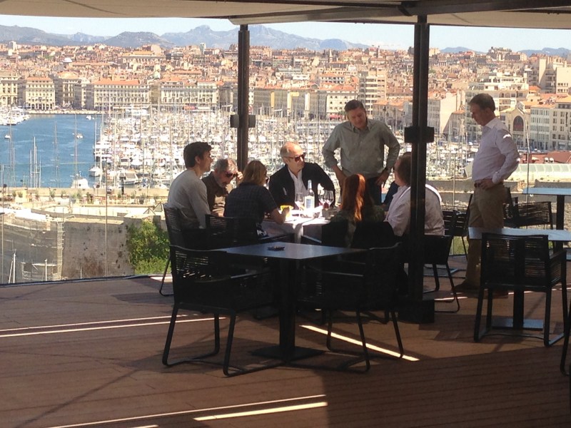 Netflix's Ted Sarandos (standing, center) and Reed Hastings (standing, right), talk to the cast and producers of "Marseille" with the city's Old Port in the background.