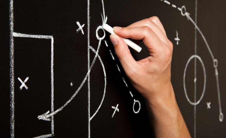 A coach drawing football plays on a chalk board