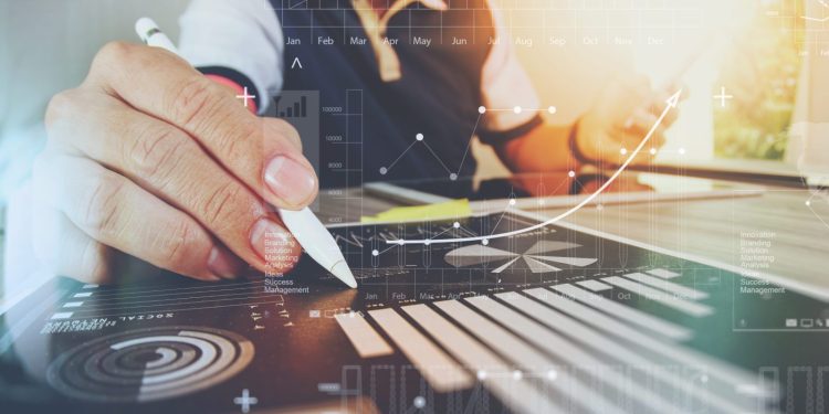 picture of a business person holding a stylus and tapping an in-desk data screen. Data analytics, data analysis