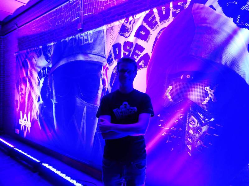 Dominic Guay, senior producer on Watch Dogs 2, stands before an image of Marcus Holloway.