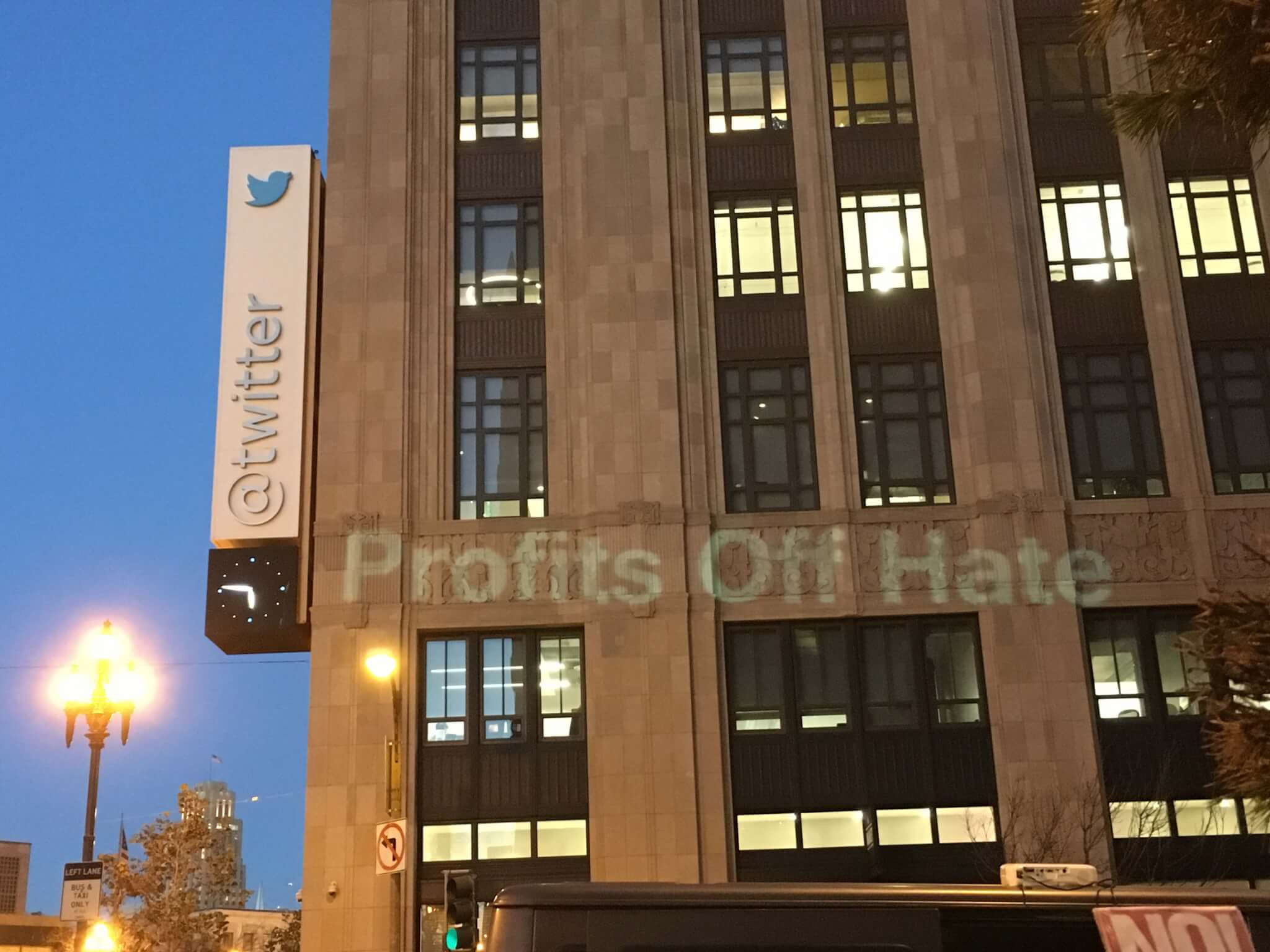 Activists protesting in front of Twitter project message saying that the company profits off of the hate expressed by Trump.