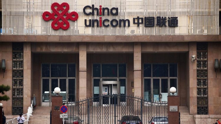 People walk past outside the China Unicom office building in Beijing, October 9, 2013. 