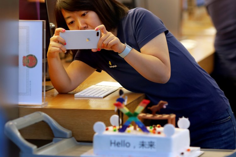 A member of Apple staff takes pictures as new iPhone X begins to sell at an Apple Store in Beijing, China November 3, 2017.
