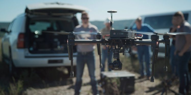 A man stands in a field operating a PrecisionHawk drone
