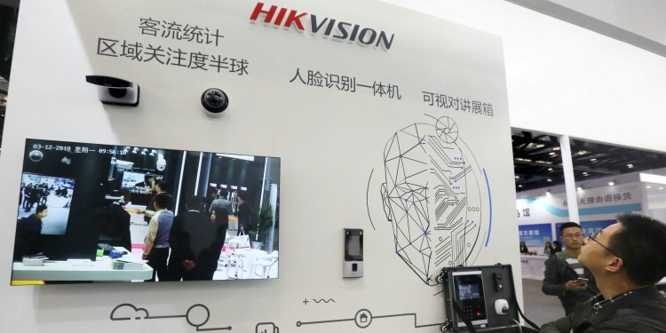 Visitors are seen at a booth of security camera supplier Hikvision Digital Technology during an expo at the National Convention Center in Beijing, China.