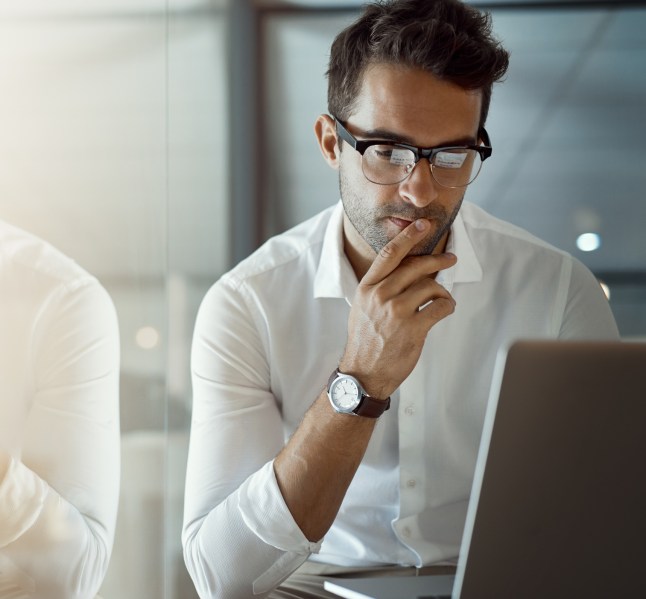 Cropped shot of a handsome young businessman looking thoughtful while working on his laptop in the office