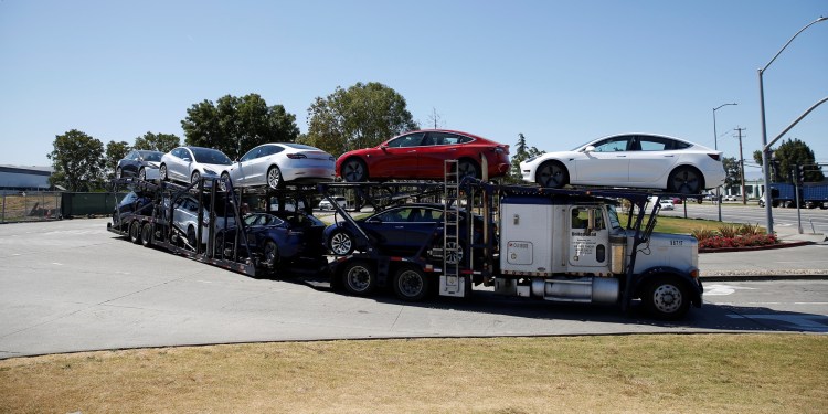 A car carrier trailer carries Tesla Model 3 electric sedans, is seen outside the Tesla factory