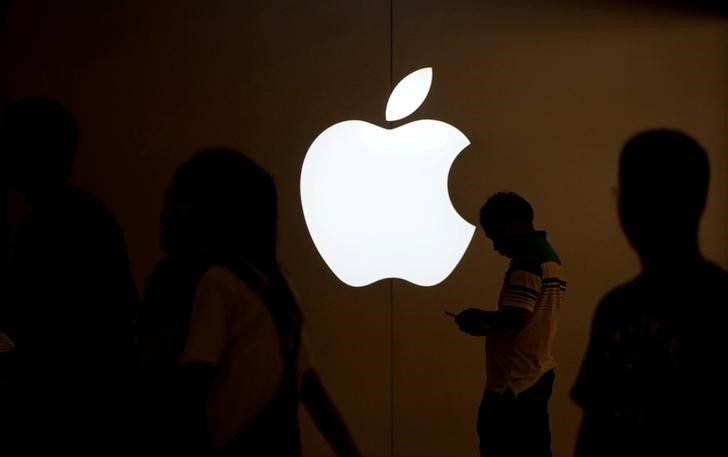 A man looks at the screen of his mobile phone in front of an Apple logo outside its store in Shanghai, China on July 30, 2017. 