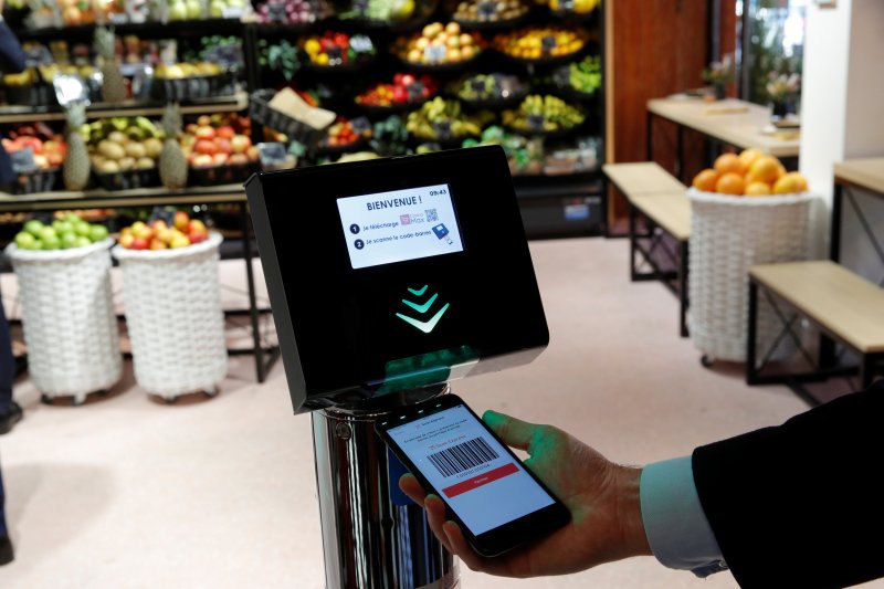 A man holds his smartphone and a Casino App at a self-scanning terminal which replaces a cashier as he shops inside a high-tech store named "Le 4 Casino" in Paris, France, October 4, 2018. 