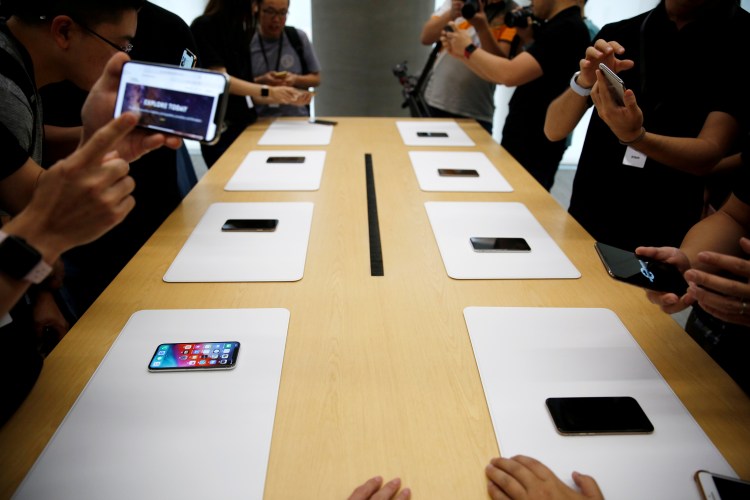 People handle the new Apple iPhone XS and iPhone XS Max during a media tour at an Apple office in Shanghai, China, September 21, 2018.