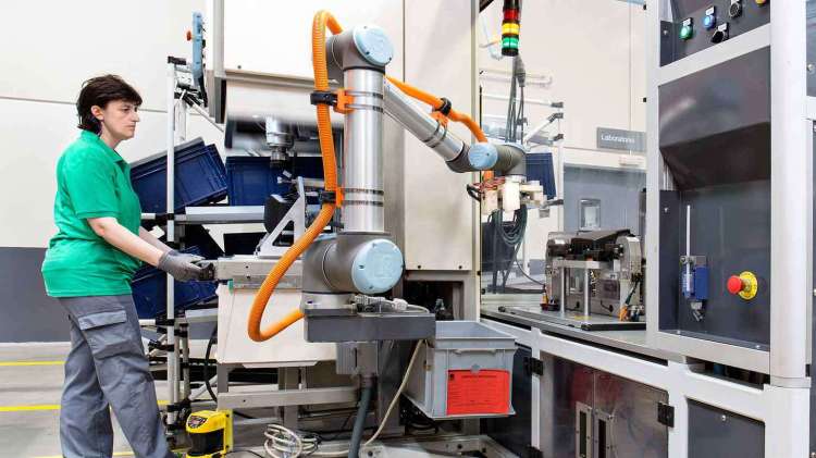 A Universal Robot works in collaboration with workers at MANN+HUMMEL.