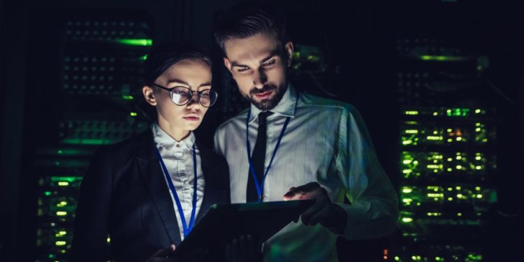 Image of cybersecurity workers consulting a computer (CISO)