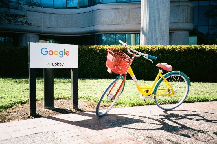 A colorful Google Bike is parked near a sign with logo for Google Inc at the Googleplex, the Silicon Valley headquarters of search engine and technology company Google Inc in Mountain View, California, April 14, 2018. (Photo by Smith Collection/Gado/Getty Images)