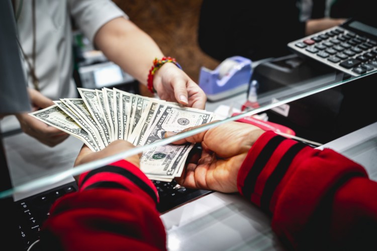bank teller receiving cash through a window