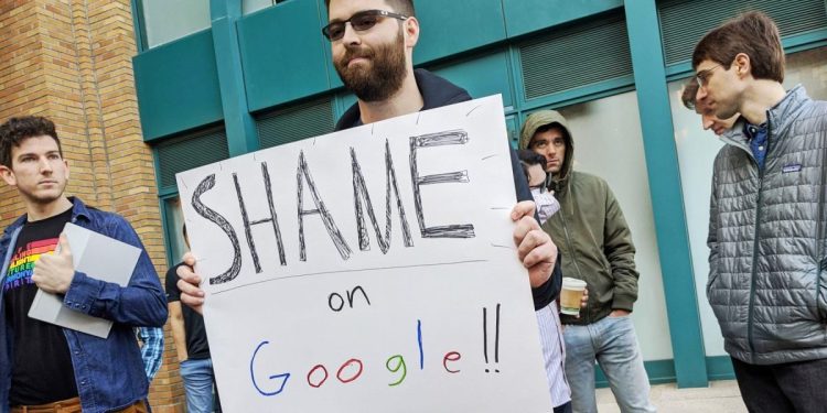 Adam Campbell holds a protest sign that reads Shame on Google