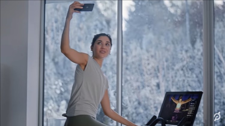 Still frame from Peloton video showing young woman on exercise bike