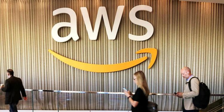 Attendees at Amazon's annual cloud computing conference walk past the AWS logo