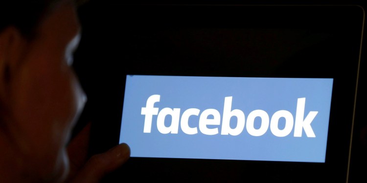 A woman looks at the Facebook logo on a screen, June 3, 2018.
