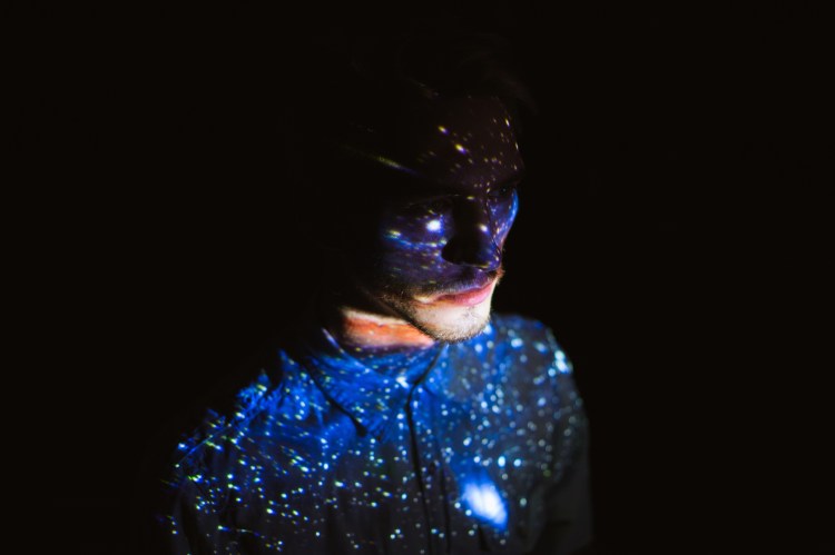 Obscured male face with points of light projected onto it
