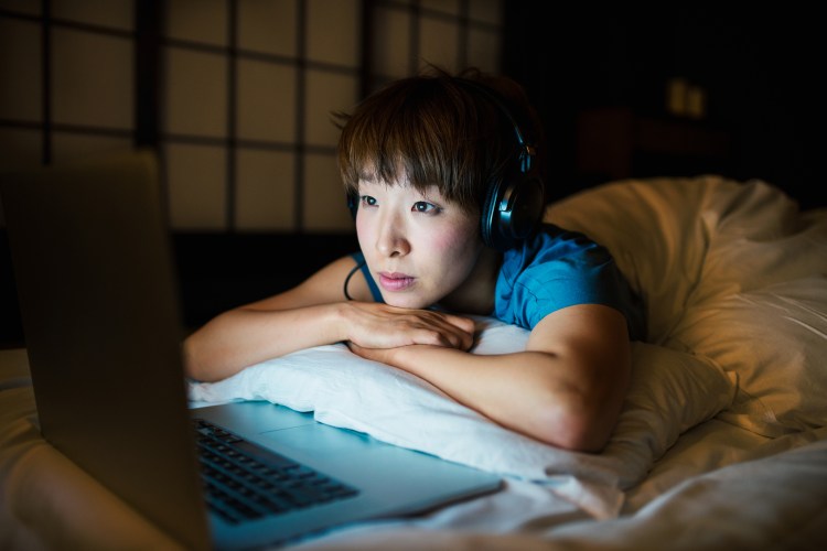 woman streaming video on her laptop in bed