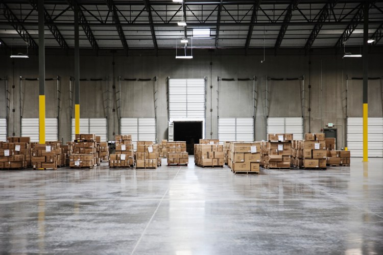 A few stacks of boxes sit in a mostly empty warehouse