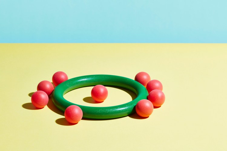 A single red sphere sits inside a green hoop surrounded by red spheres