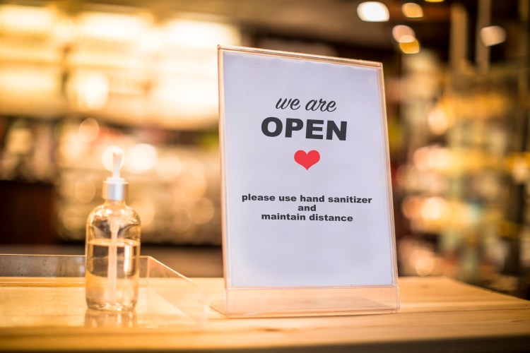 Hand sanitizer and reopening sign in shop.