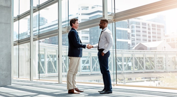 Shot of two businessmen shaking hands in a modern workplace