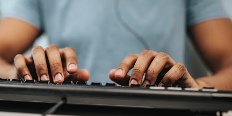 Close up of black programmer using computer keyboard.