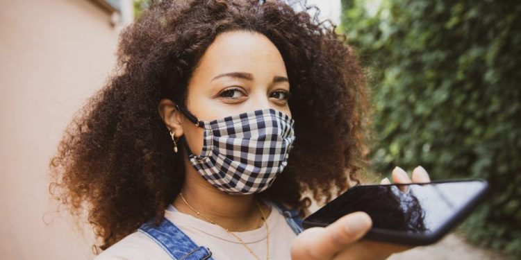 Portrait of a young afro hair woman in the city wearing a cloth protective mask in Italy during Covid-19 coronavirus pandemic
