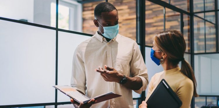 Image of two businesspeople wearing masks while they work during the COVID-19 pandemic.