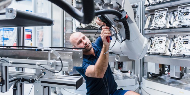 Man working at industrial robot in factory