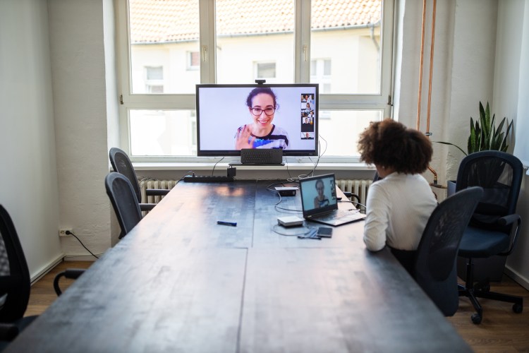 Businesswoman having a meeting with coworkers over a video call in office board room. Planning meeting over a video call in office