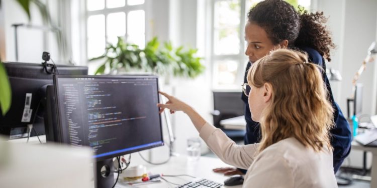 IT team leaders look and discuss code on a desktop computer.