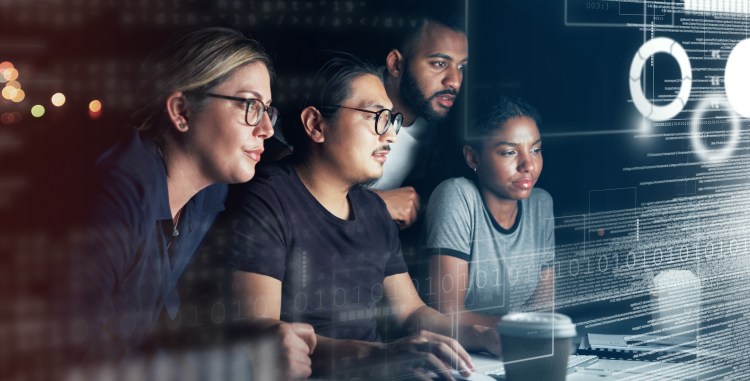 Shot of a group of programmers working together on a computer code at night