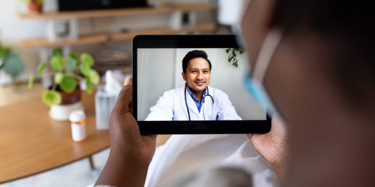 Sick patient having online consultation with doctor on their digital tablet. Close up of a person consulting with their doctor over a telemedicine on their tablet pc.