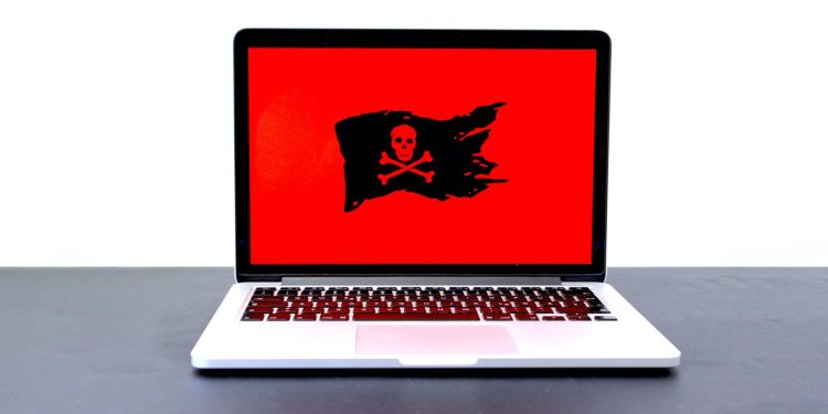 Laptop displaying a pirate flag on a red screen, possibly indicating malware, hackers or a different computer problem.