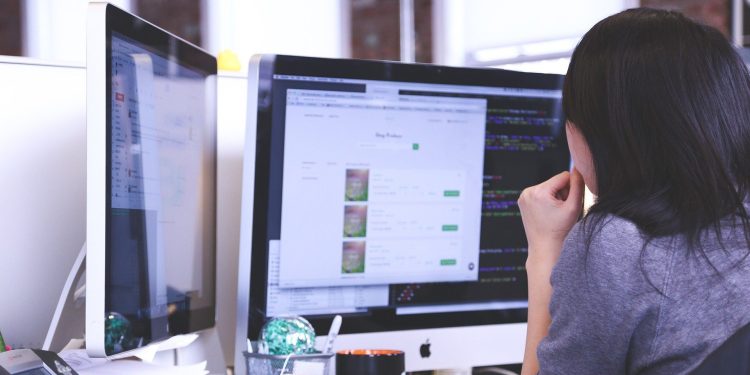 Person working at a desk with two monitors and an office phone