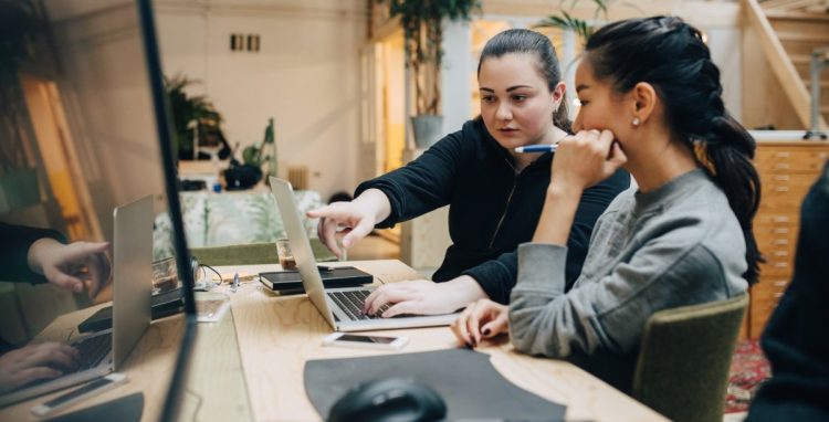 coworkers discussing coding on laptop while sitting in office
