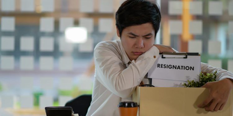 Upset person with a box. Sign on the box says "Resignation"