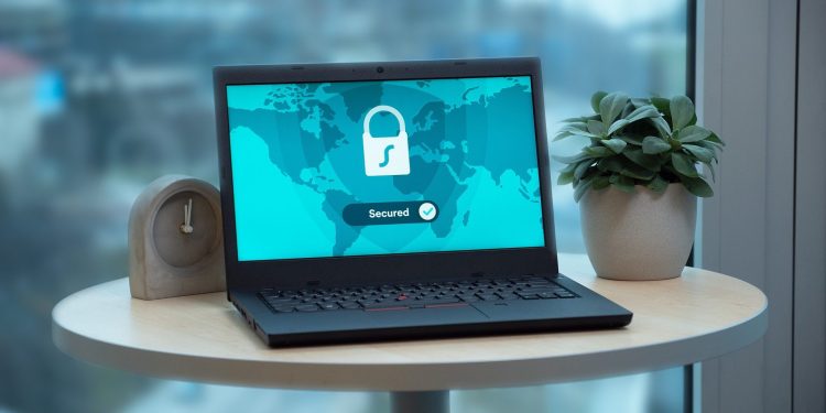 Photo of a laptop on an end table with a screen that says secured and has a lock. Represents computer security, protection from ransomware and phishing