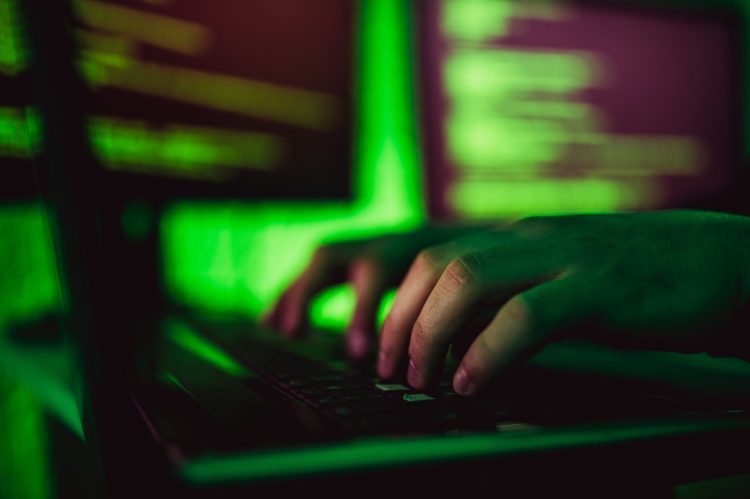 Hands of hacker typing on keyboard of laptop, close up.